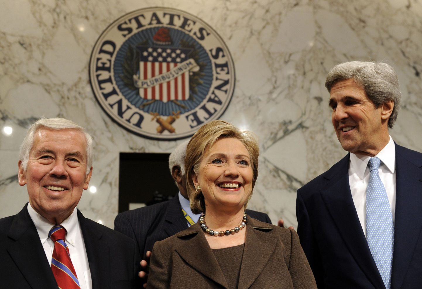 USA riigisekretäriks tõusnud Hillary Clinton (keskel) seismas kõrvutu senati väliskomisjoni esimehe, demokraat John Kerry (paremal) ja juhtiva vabariiklase Richard Lugari (vasakul) vahel.