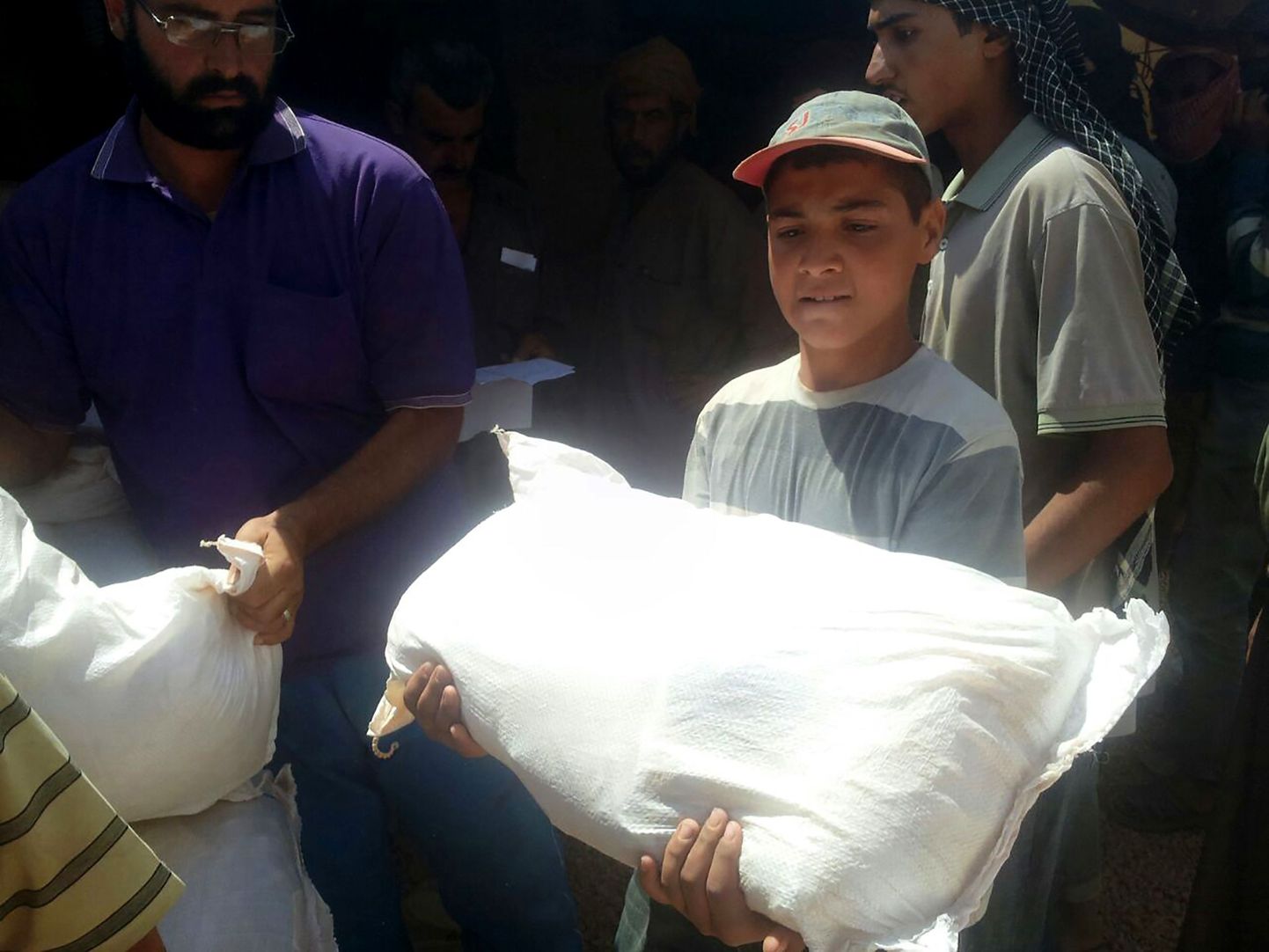 Süüria poiss hoidmas toidukotti, mis täna Jordaanias kraanaga Süüriasse tõsteti.