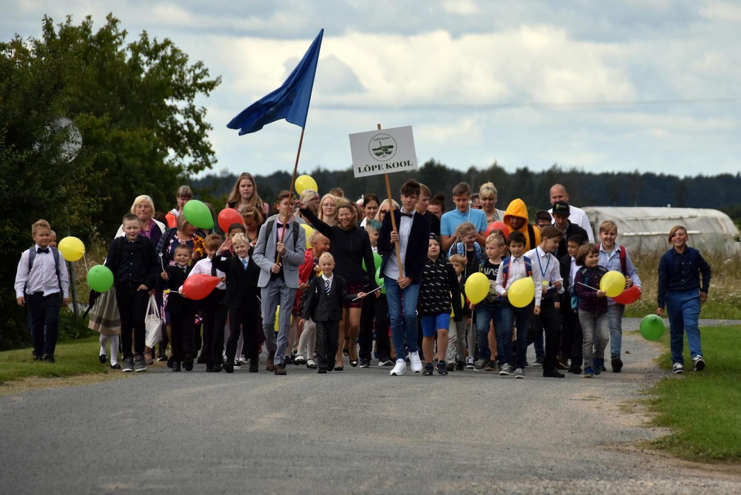 Lõpe koolipere marssis värviliste õhupallidega ja kooli lipu lehvides klubist koolimajja.