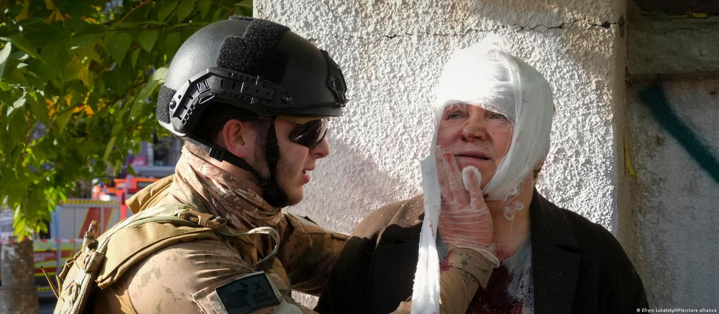 Доброволец оказывает медицинскую помощь раненой во время ракетных обстрелов Киева 10 октября женщине