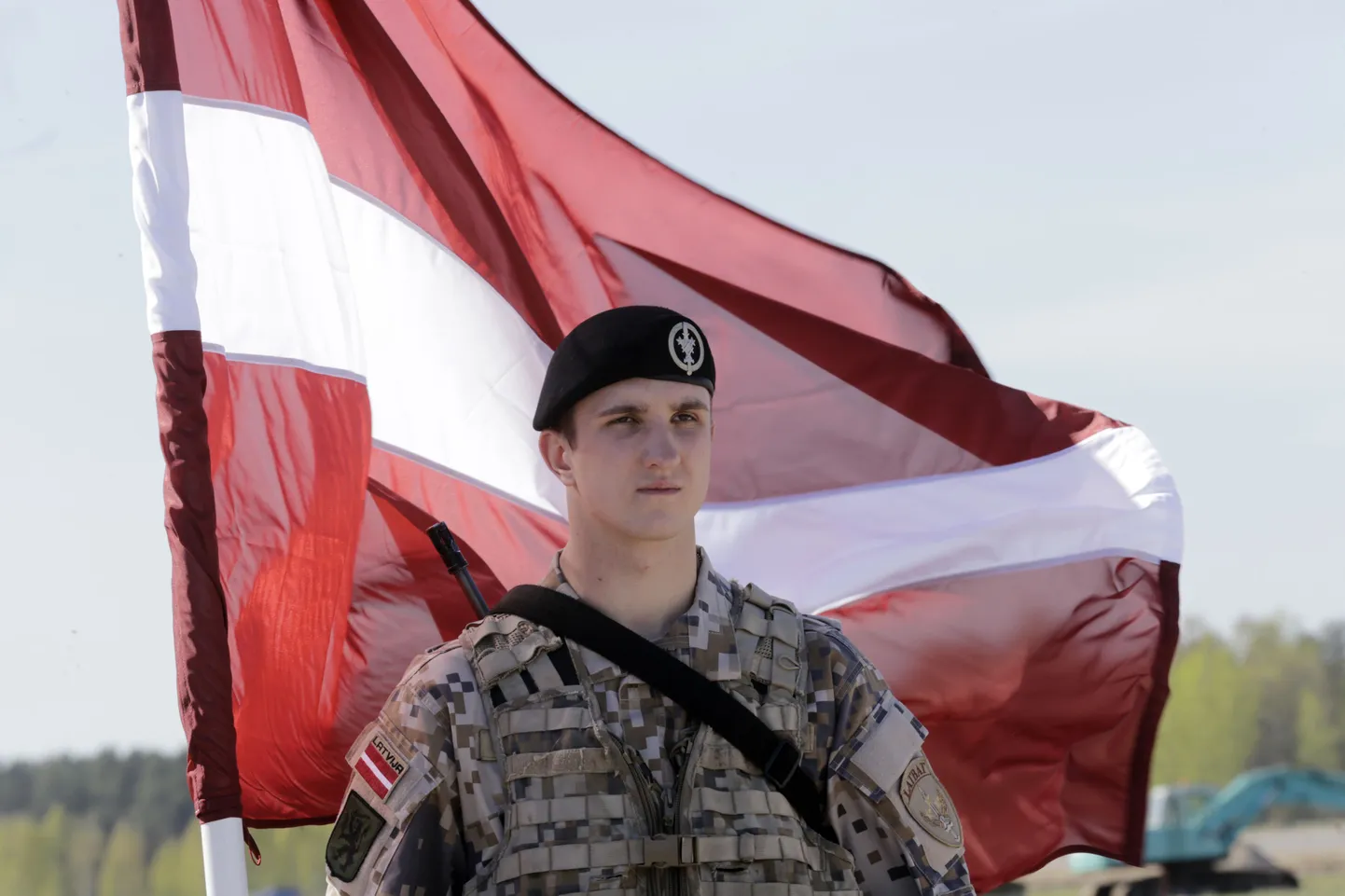 Солдат на фоне латвийского флага.