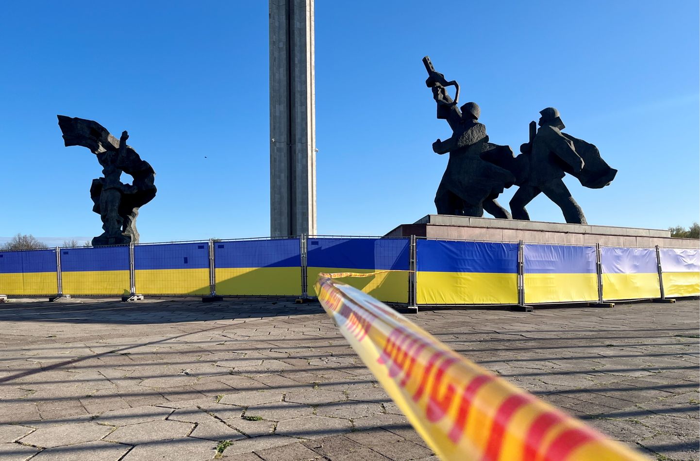 Policijas norobežojošā lenta un plakāti Ukrainas karoga krāsās pie pieminekļu kompleksa Uzvaras parkā dienu pirms 9. maija.