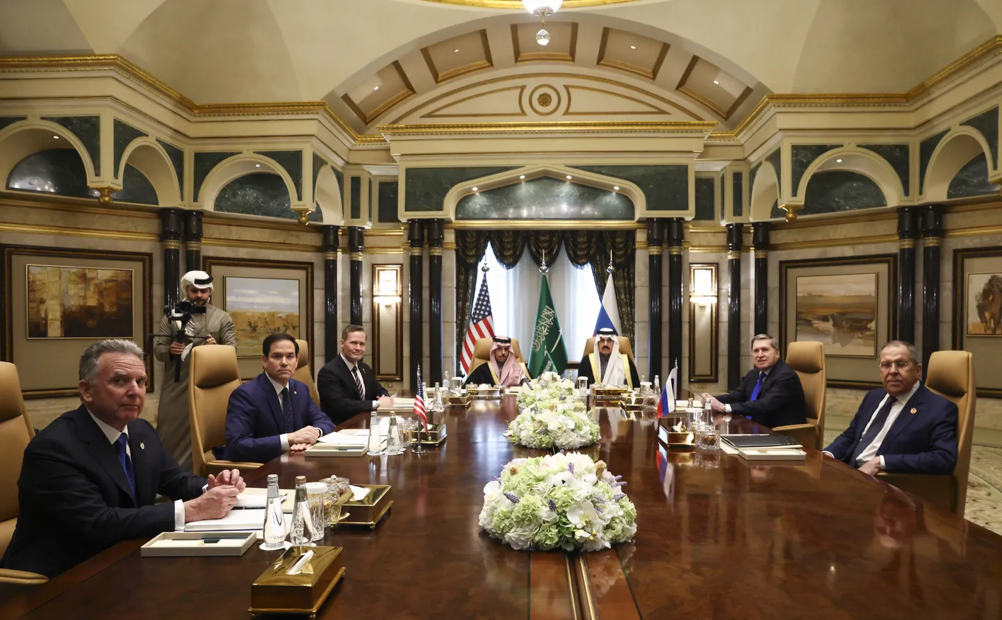 Ameerika Ühendriikide (vasakult: Steve Witkoff, Marco Rubio, Mike Waltz) ja Venemaa (paremalt: Sergei Lavrov ja Juri Ušakov) esindajad. Laua otsas Saudi Araabia välisminister prints Faisal bin-Farhan al-Saud ja riikliku julgeoleku nõunik Mosaad bin-Mohammad al-Aiban.