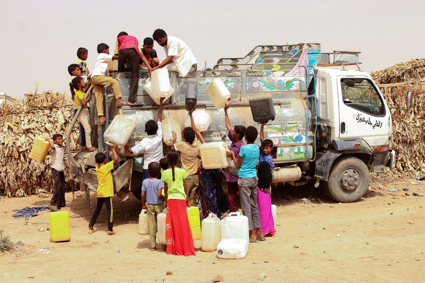 Hodeidast lahkunud jeemenlased täidavad veekanistreid Hajjiah' laagris.