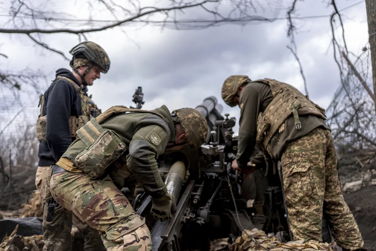 Ukrainian servicemen of Khartia brigade loading shell into an American M101A Howitzer before firing towards Russian positions in Kharkiv region, Ukraine, Wednesday, March 12, 2025.