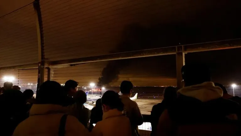 Пассажиры наблюдают за горящим самолетом со смотровой площадки.