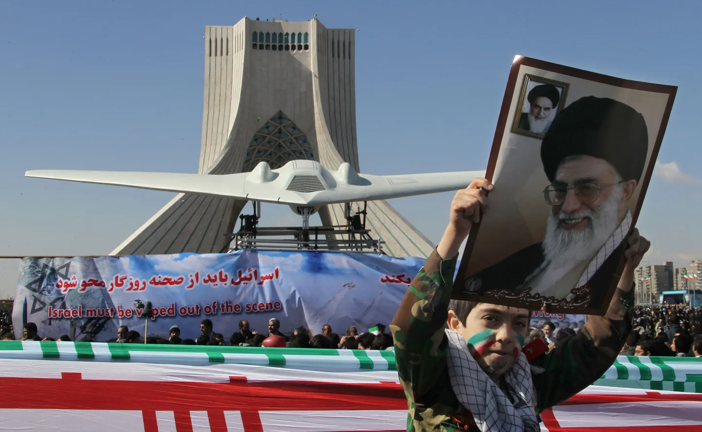Ühendriikide mehitamata luurelennuki RQ-170 Sentinel koopia täna Teherani keskväljakul. Pildil lehvitab poiss Iraani kõrgeima juhi ajatolla Ali Khamenei pildiga plakatit.