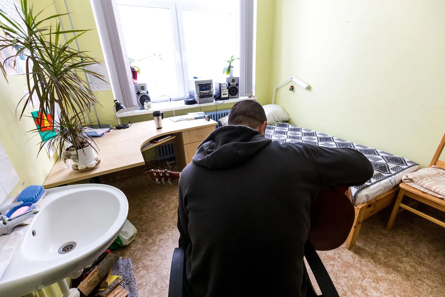 Jämejala rehabilitatsioonikeskuses ravil viibiv uimastisõltlane, 37-aastane Dmitri mängib oma toas kitarri.