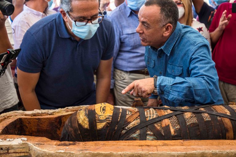 Министр туризма Египта Халед аль-Анани (слева) и генеральный директор Управления древностей Мустафа Вазири (справа) наблюдают за мумией человека, похороненного более 2500 лет назад.