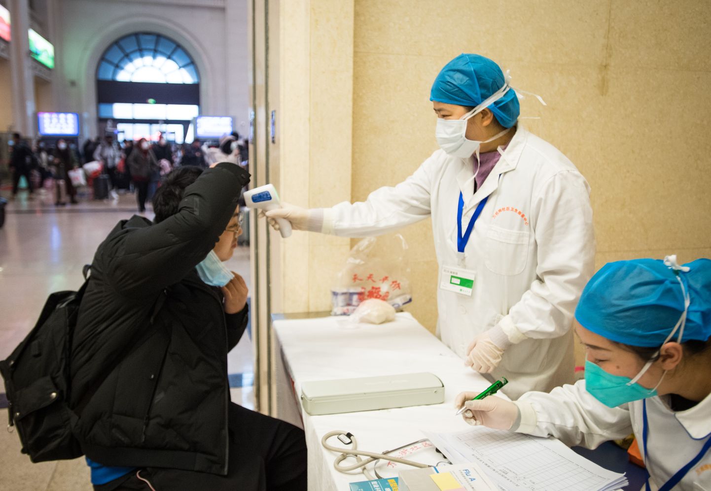 Arstid mõõtmas reisjate kehatemperatuuri Wuhani rongijaamas.