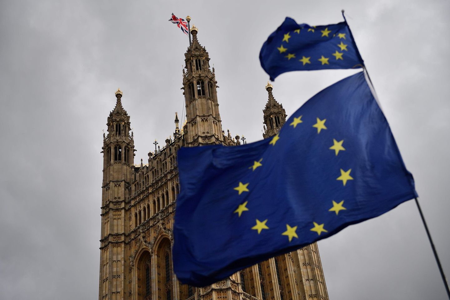 Ühendkunigriigi lipp parlamendihoonel ja Euroopa Liidu lipud meeleavaldajate käes.