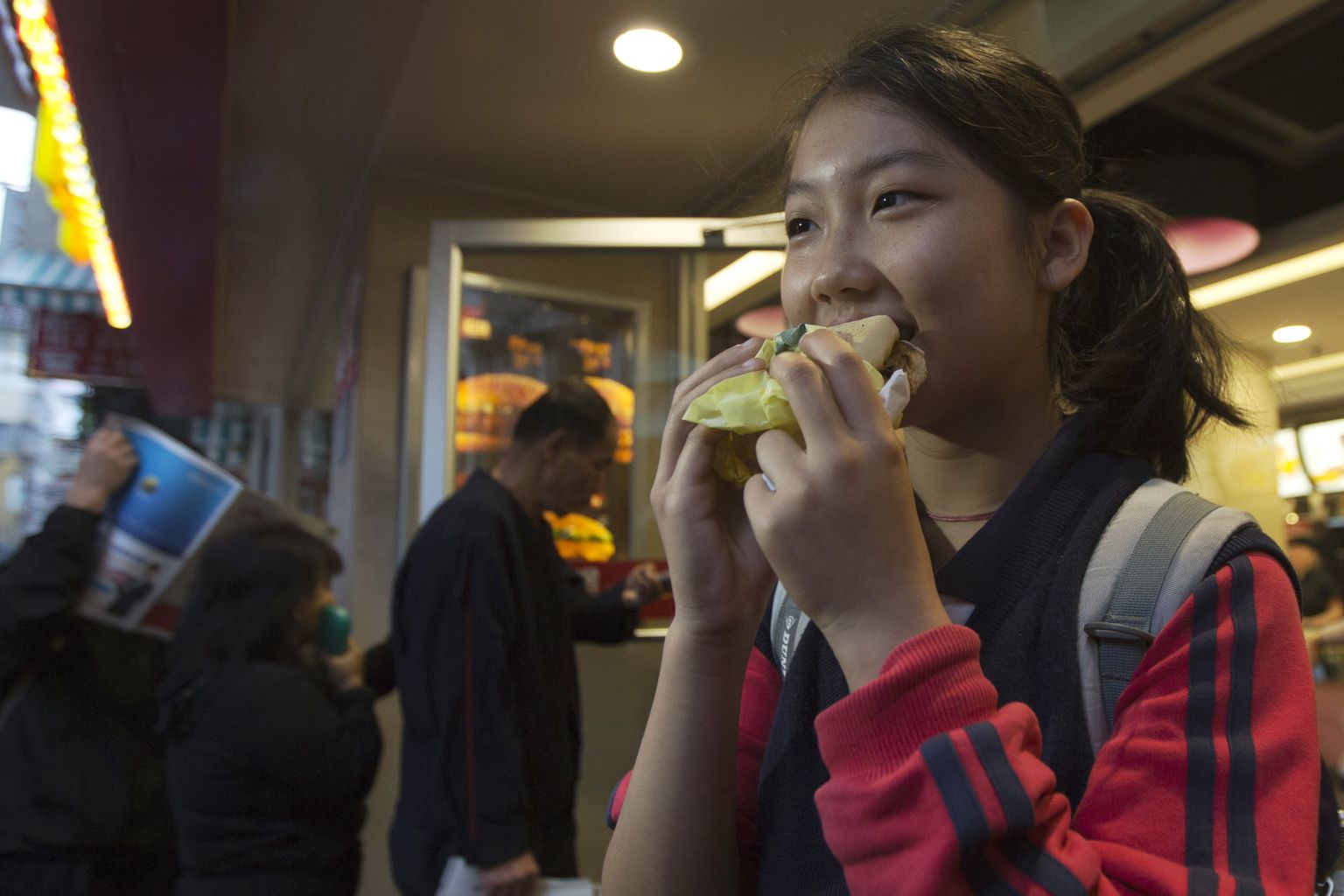 Pilt on illustreeriv: tüdruk nautimas McMuffini burgerit.