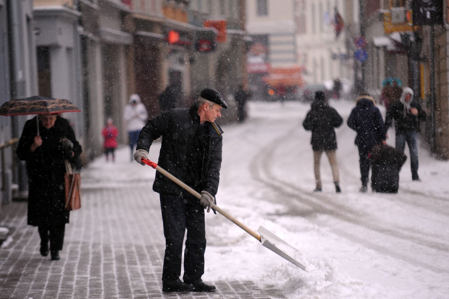 Vīrietis tīra sniegu Kaļķu ielā