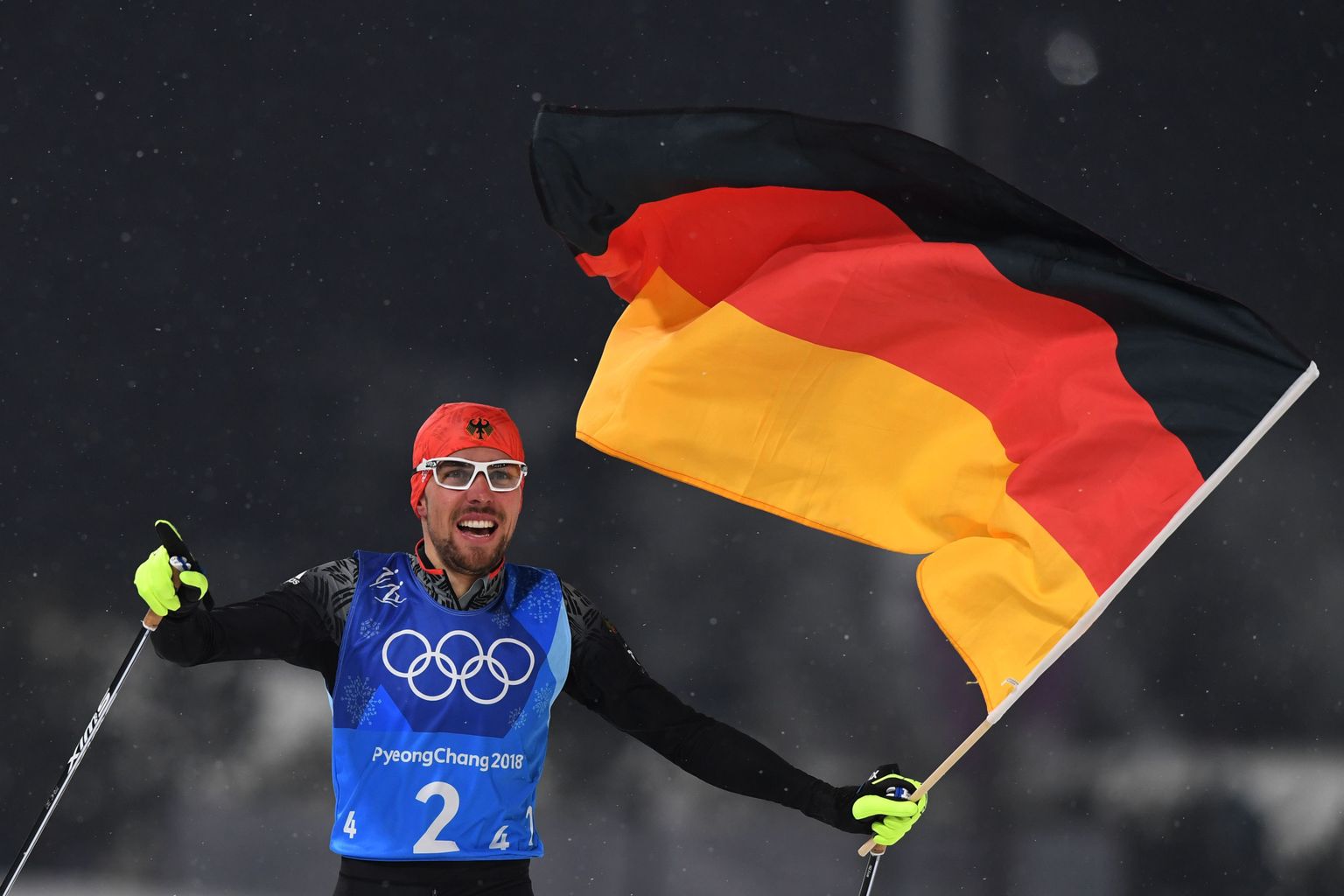 Germany's Johannes Rydzek holding a German flag crosses the finish line in the nordic combined team Gundersen LH/4x5km cross country at the Alpensia Cross-Country Skiing Centre during the Pyeongchang 2018 Winter Olympic Games on February 22, 2018 in Pyeongchang. / AFP PHOTO / Christof STACHE