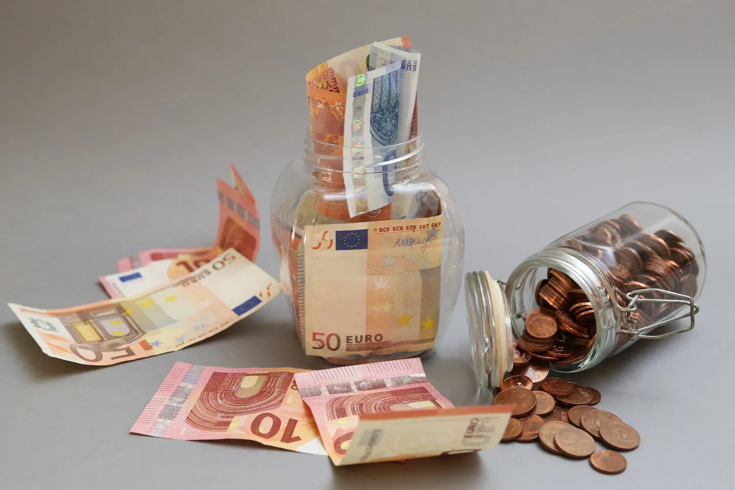 Eiro banknotes un monētas burkā. Ilustratīvs attēls.