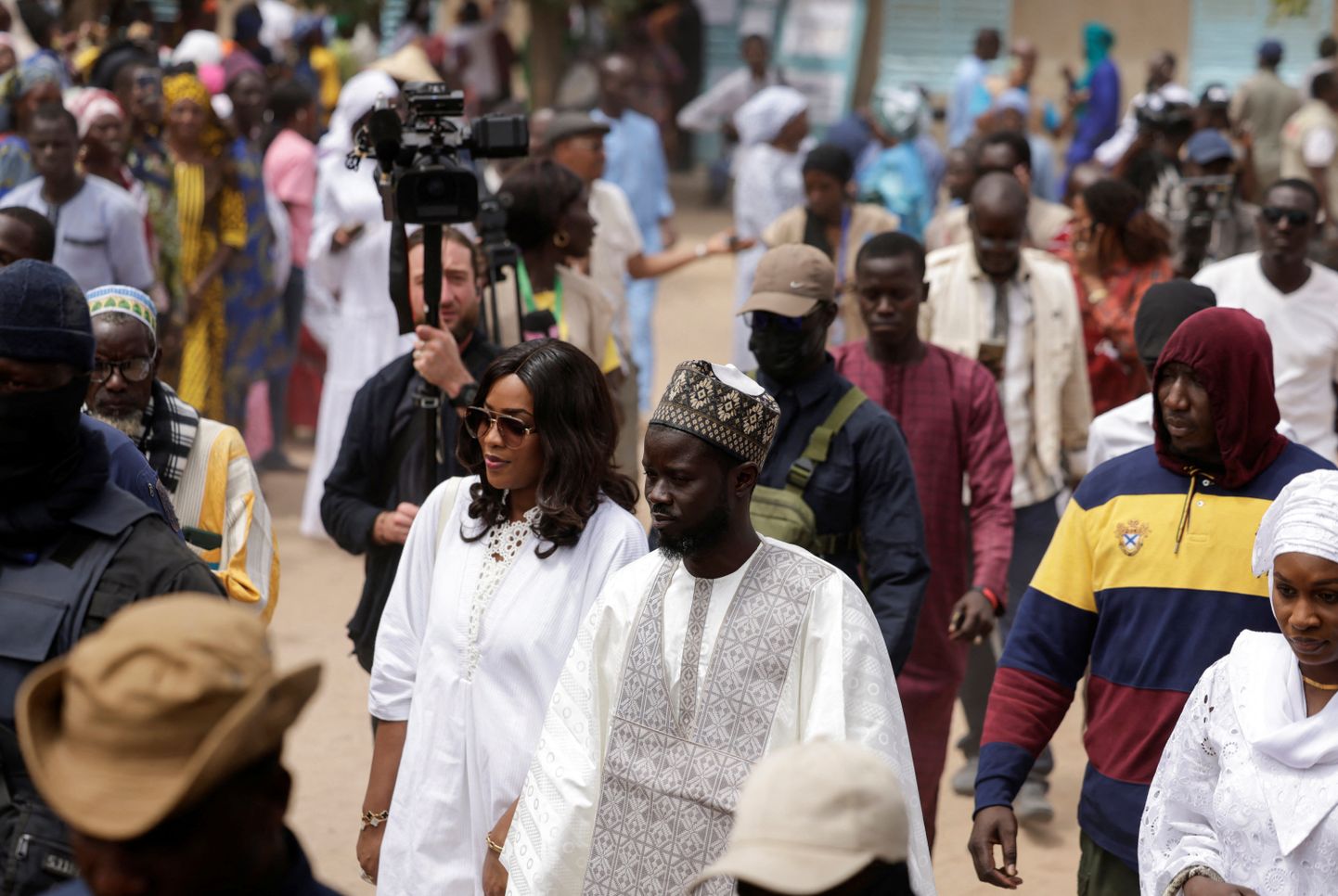 Bassirou Diomaye Faye ja tema naised teel valimisjaoskonnast välja.