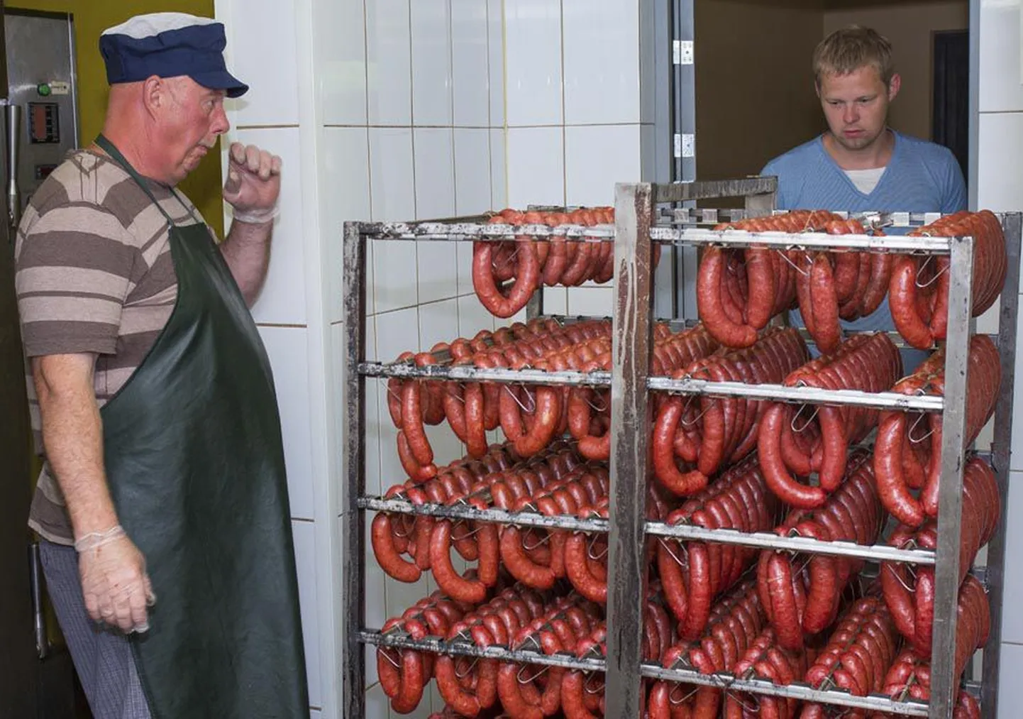 Tiit Aavasalu (vasakul) ja Mehis Luuken võtavad ahjust välja äsja valminud suitsuvorste.