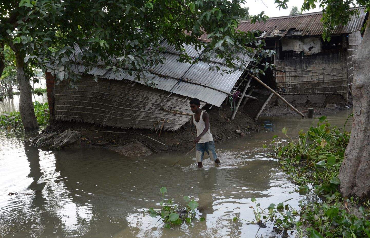 Vīrietis Indijā pie savas plūdu bojātās mājas.