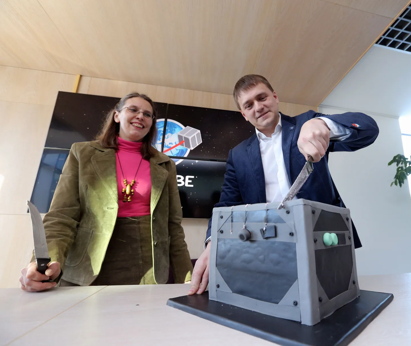 Eesti esimese tudengisatelliidi Estcube-1 projekti juhtinud Silver Lätt eile Tõraveres kuubikukujulist torti lahti lõikamas. Tema tegevust jälgib Tartu observatooriumi tugiteenuste osakonna juhataja Tiia Lillemaa.