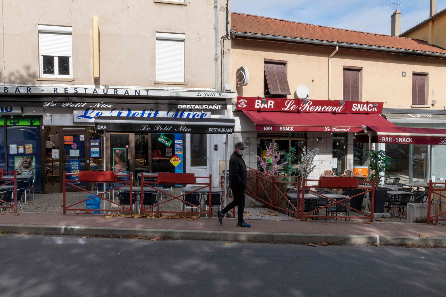 Vīrietis maskā iet garām slēgtiem veikaliem un bāriem Francijā