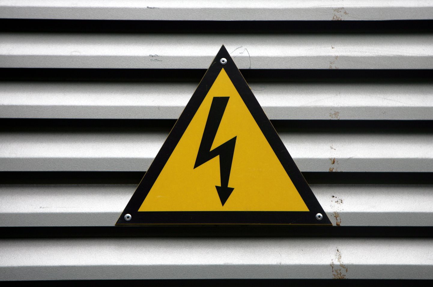 Emaljēta brīdinājuma zīme "Uzmanību! Elektrība" par augsto spriegumu pie transformatora apakšstacijas durvīm.