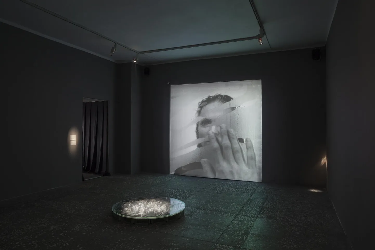 Esiplaanil «Kaev/Well». Graveeritud peegel, klaas, 2022. Taustal «Rituaal/The Ritual». HD video, 2022.
