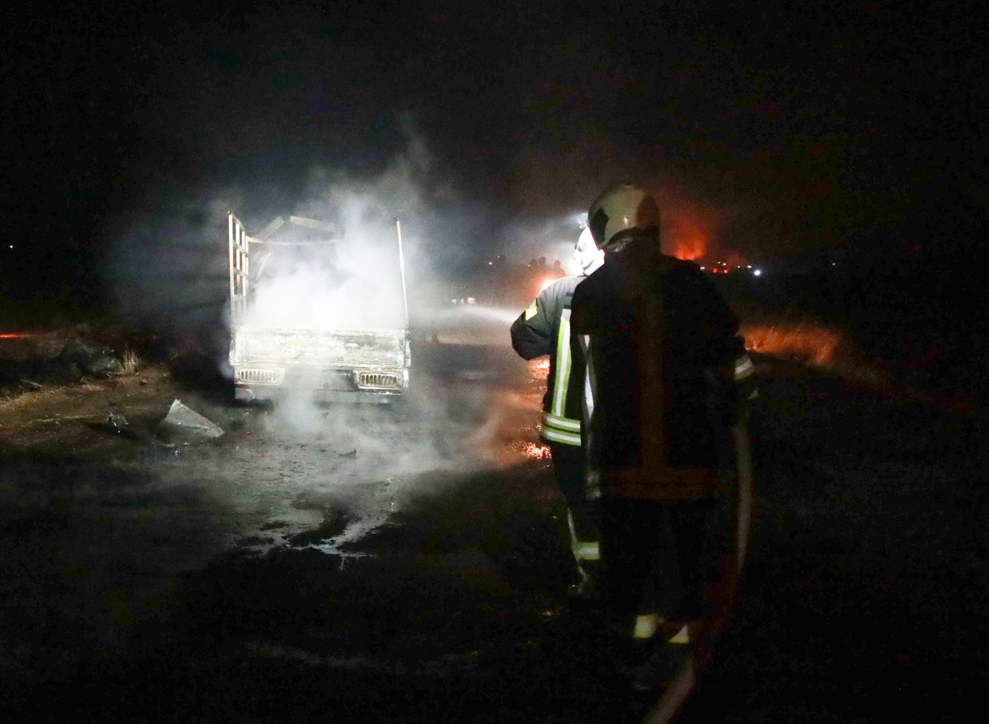 Tuletõrjujad kustutamas ühte Ayn al-Bayda külas tabamuse saanud sõidukitest.