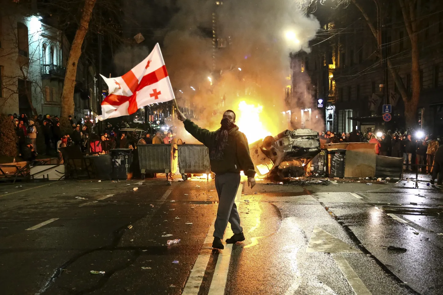 Mees Gruusia lipuga põleva auto ja barrikaadi ees välisagentide seaduse vastastel protestidel Thibilisis 9. märtsil 2023. aastal. Pilt on illustratiivne.
