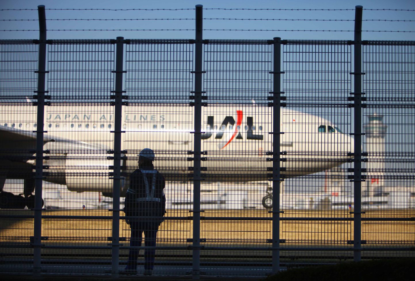 Töötaja Tokio Hanada lennujaamas vaatamas Japan Airlinesi lennuki möödumist.