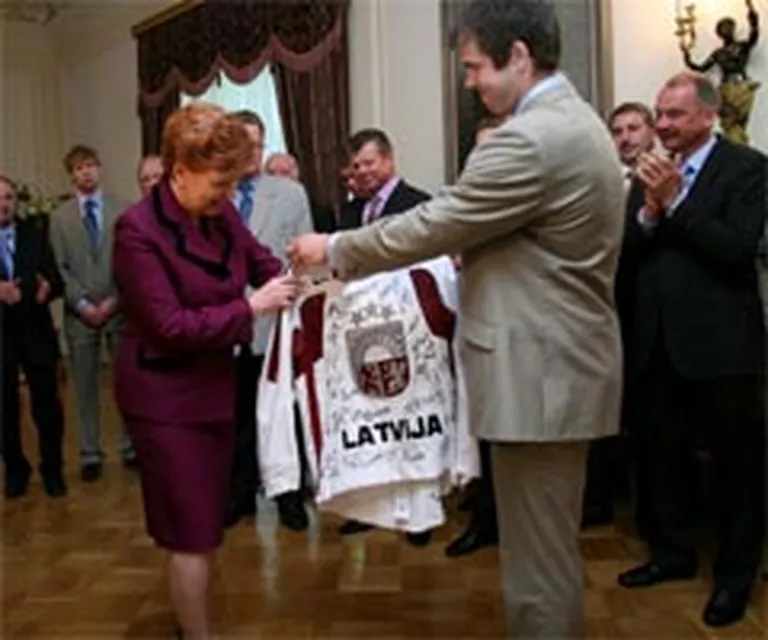 Latvijas izlases kapteiņa asistens Jānis Sprukts (no labās) Valsts prezidentei Vairai Vīķei-Freibergai pasniedz izlases kreklu ar visu dalībnieku autogrāfiem. 