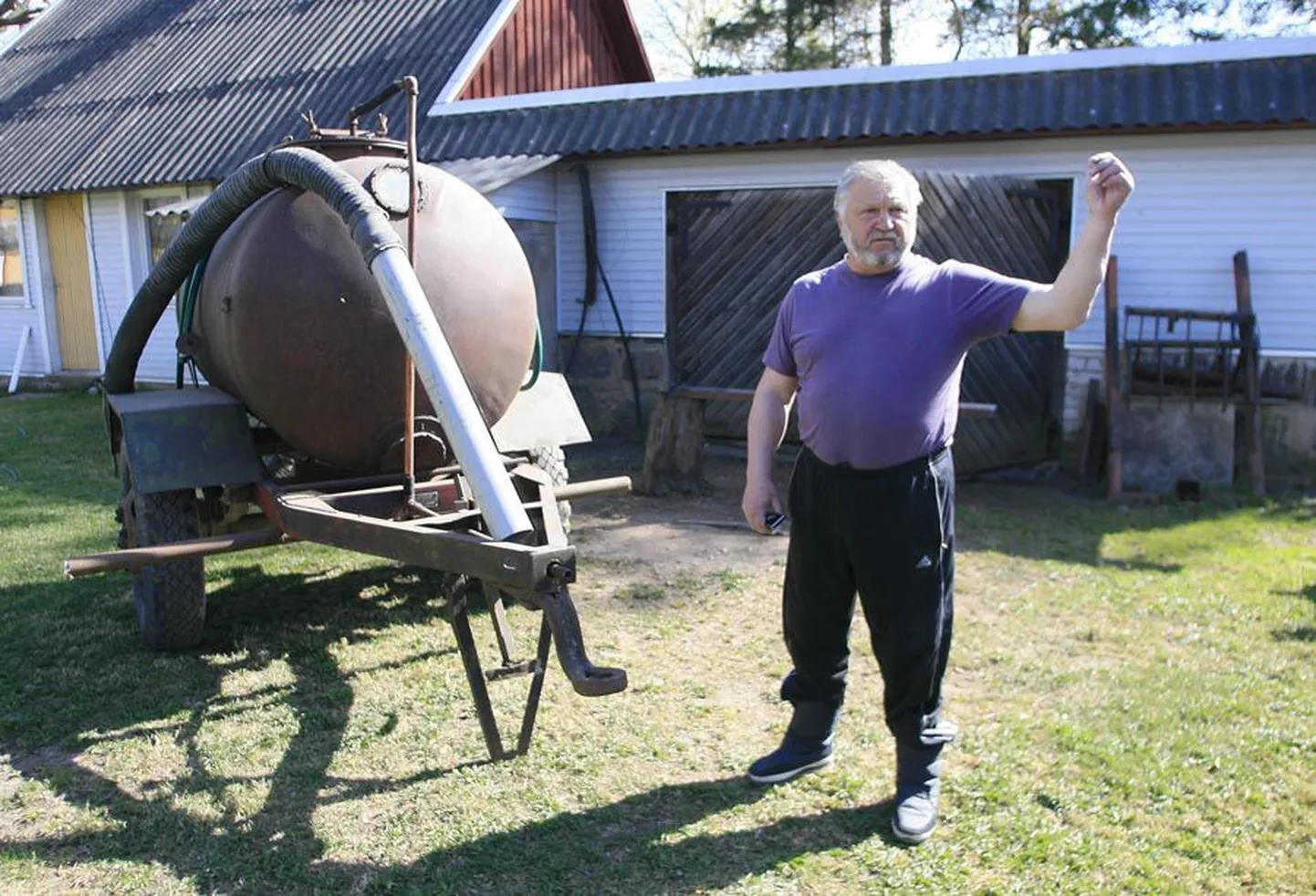 Hillar Zemesch näitab traktori veetavat veepaaki, millega ta tolmavat teed kastab.