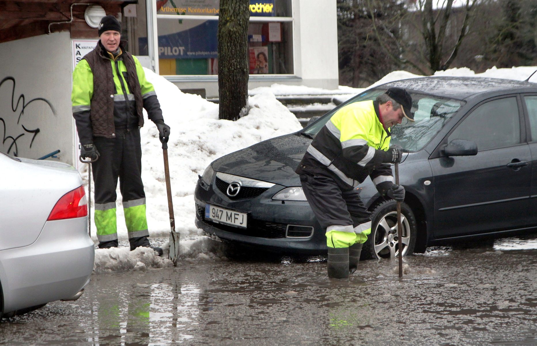 Töömehed puhastasid Pärnus Laial tänaval sulavee ärajuhtimiseks lumest ja jääst kaevukaasi.