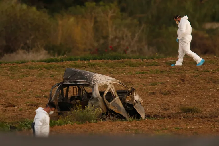 Uurijad toimetamas Daphne Caruana Galizia mõrvapaigal tema auto söestunud vraki ümber.
