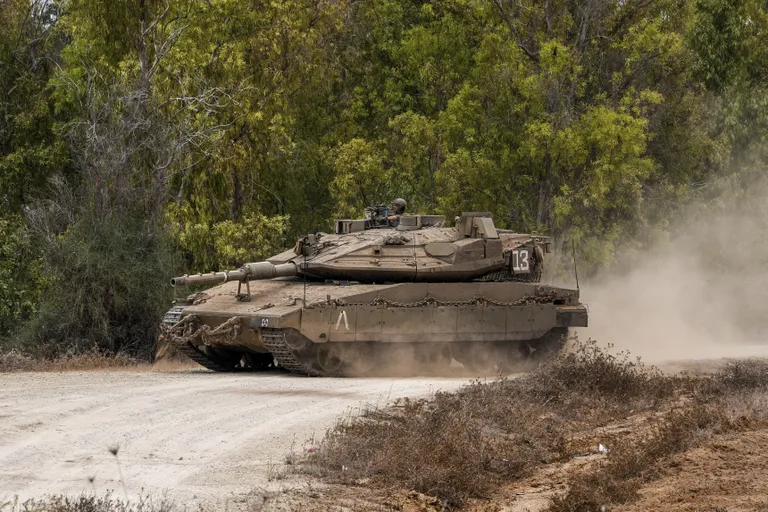Израильский танк пересекает дорогу, продвигаясь к плацдарму у израильской границы с сектором Газа, юг Израиля, понедельник, 9 октября 2023 года