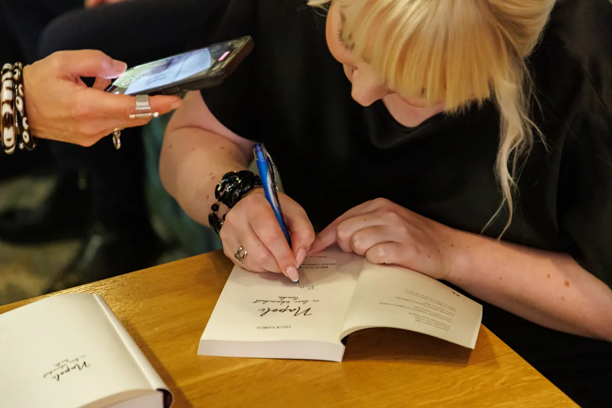 Evelin kirjutab oma raamatusse isiklikke pühendusi ning annab autogramme.