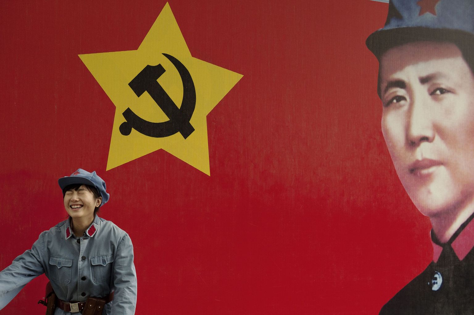 Turist riietatuna Punase Armee sõduriks Mao Zedongi pildi ees.