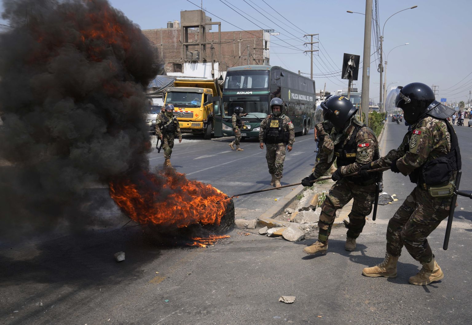 Politseinikud eemaldamas Peruu pealinnas Limas rahutuste ajal põlema pandud rehvi.