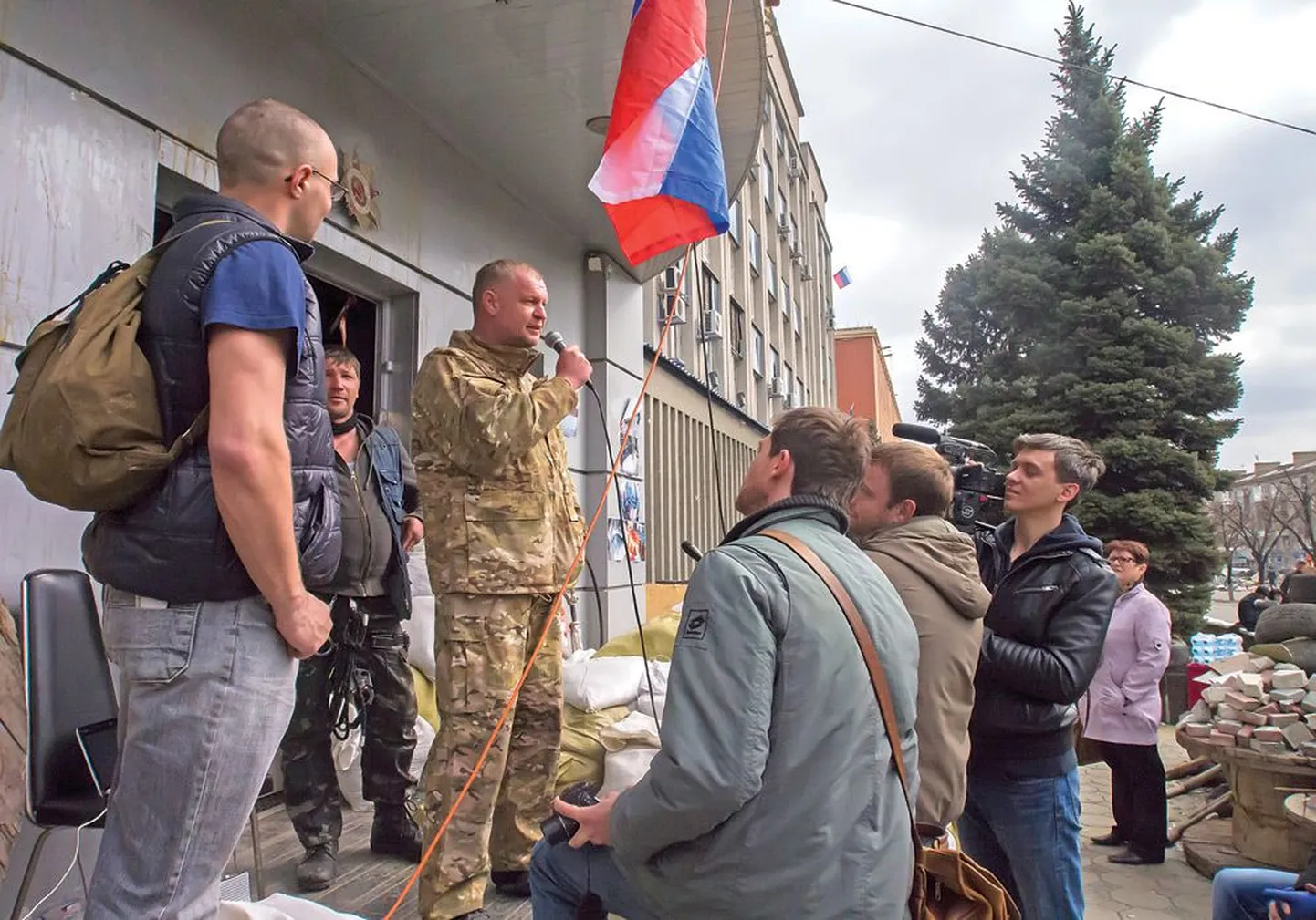 Пророссийский активист, называющий себя Василием, говорит с единомышленниками и журналистами на крыльце штаб-квартиры службы безопасности в Луганске.