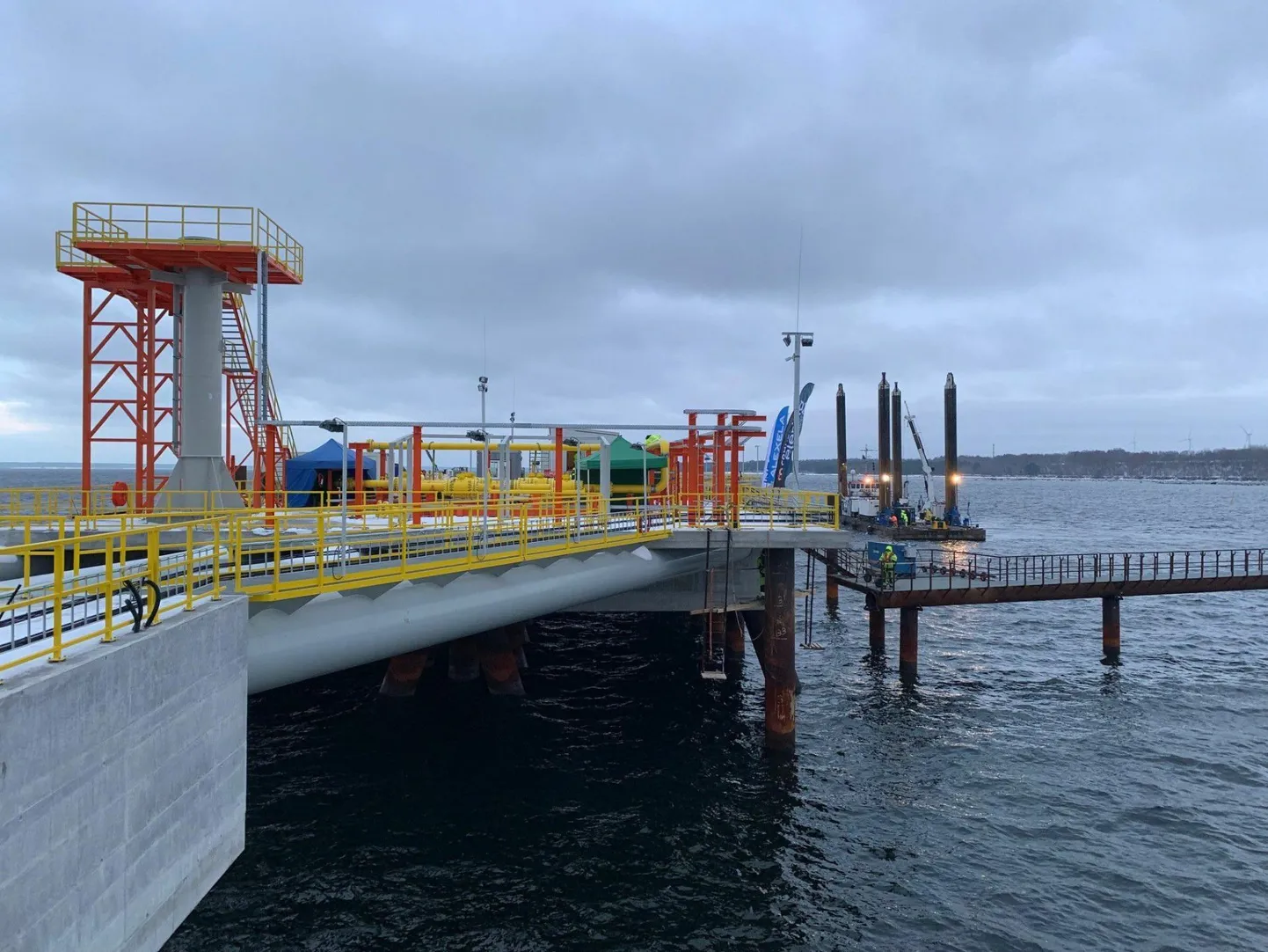 Paldiski LNG-terminali kai. Vasakul olev kollase piirdega torn on laadimisvarre alus koos teenindusplatvormiga.