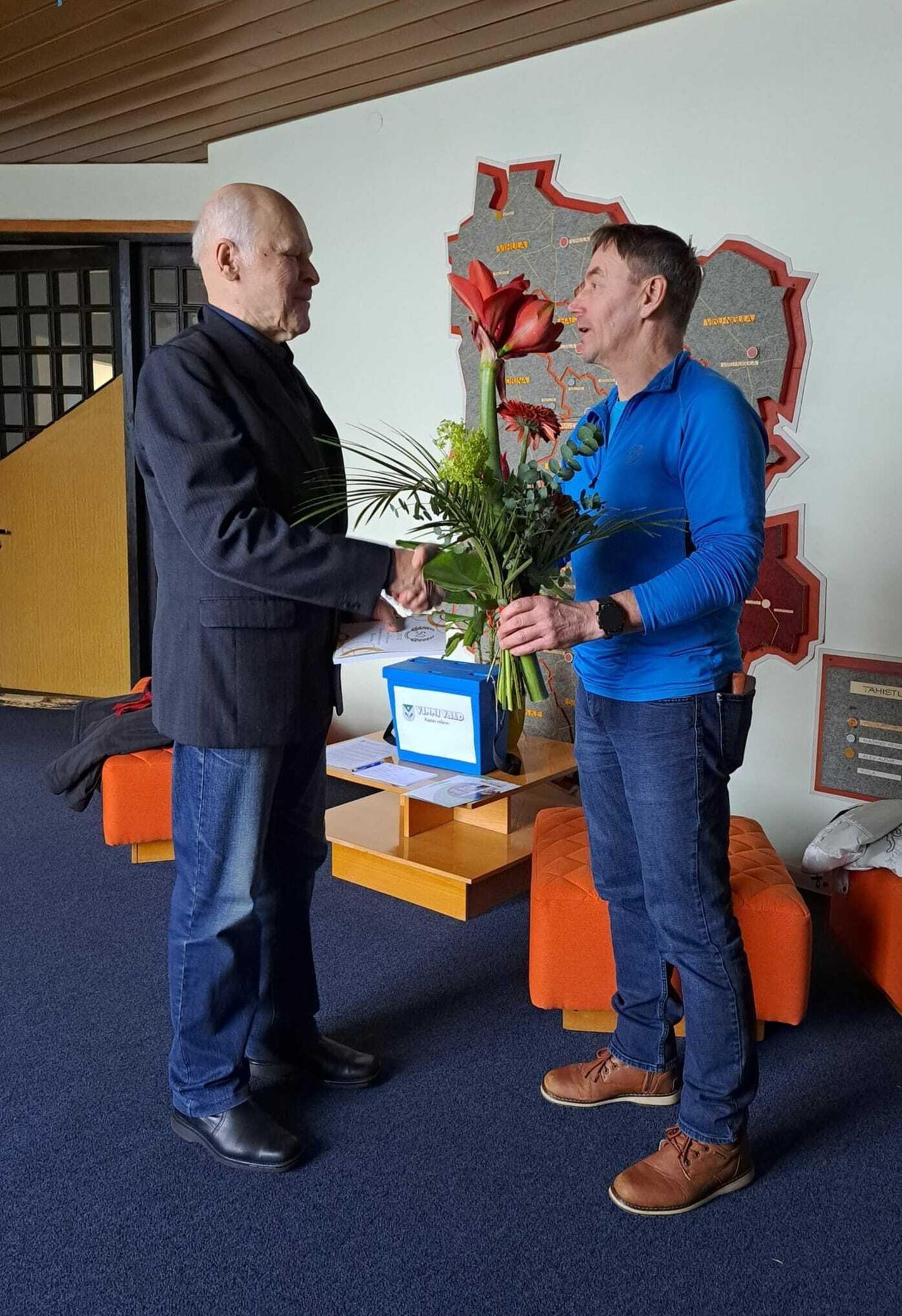 Jüri Mägi (vasakul) saab õnnitlused ja lilled vallavalitsuse spordinõunikult Uno Muruveelt.
