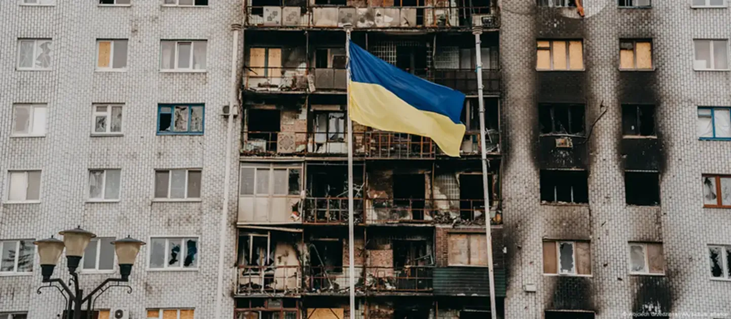Украинский флаг на фоне пострадавшей от российского удара многоэтажки в Торецке