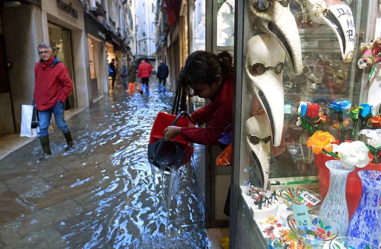 Veneetsia poeomanik tõstmas ämbriga kauplusest tulvavett välja