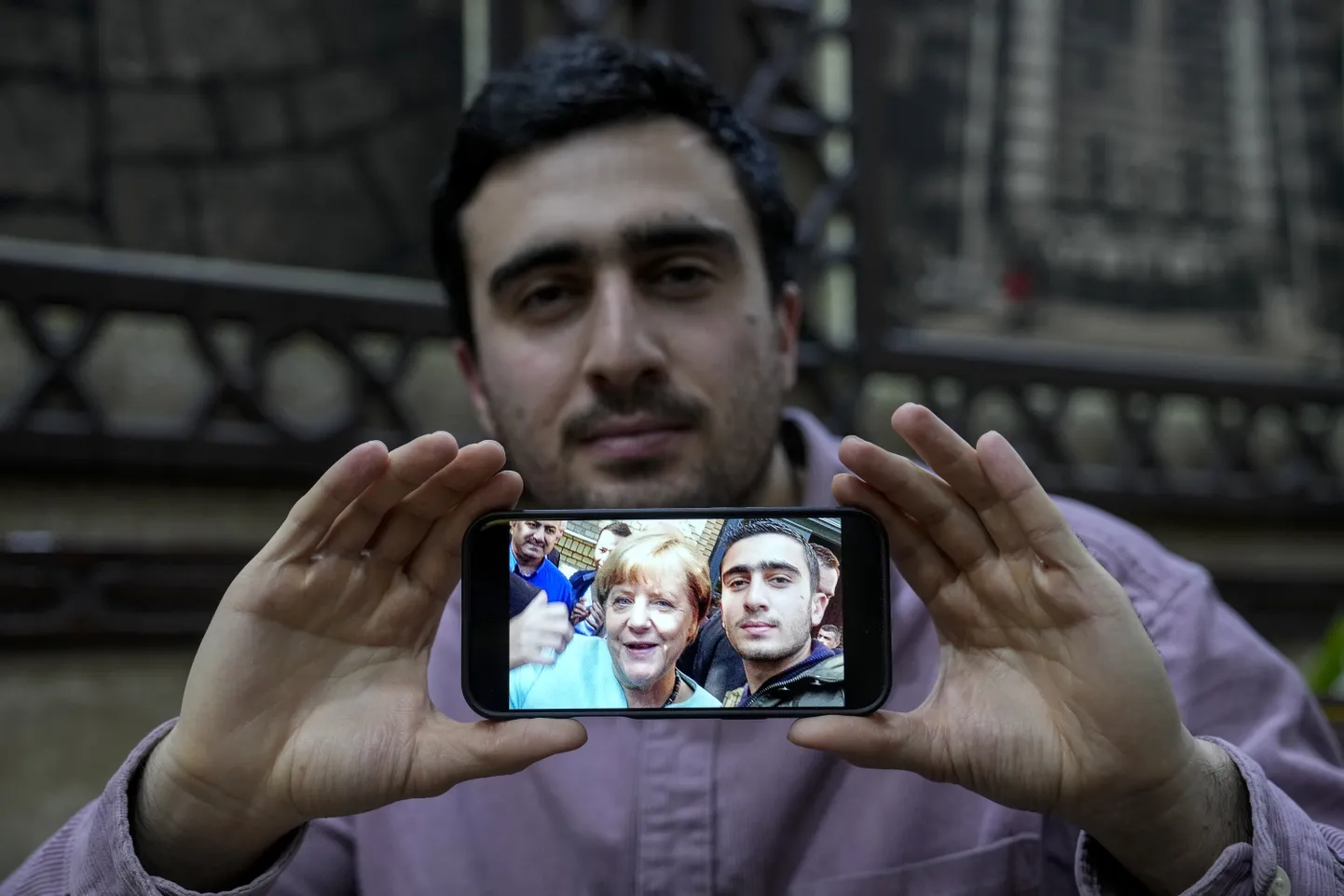 Анас Модамани (27), живущий в Германии, с известной фотографией, на которой он запечатлен с канцлером Германии Ангелой Меркель после бегства из Сирии в Берлин.
