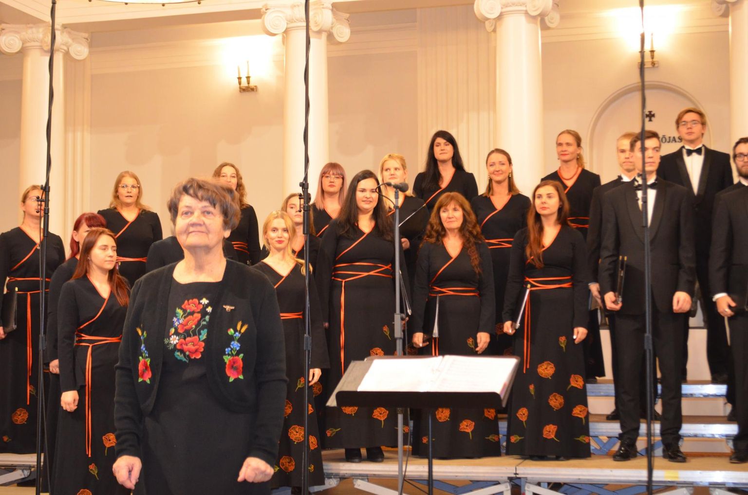 Laulu «Oo, muusika, sa õilis kunst» juubelikontserdi avaloona esitanud TÜ kammerkoori ees on koori asutaja Vaike Uibopuu.
 