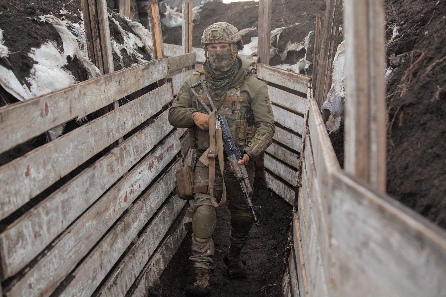 A service member of the Ukrainian armed forces walks with a weapon at fighting positions on the line of separation near the Moscow-controlled city of Donetsk.