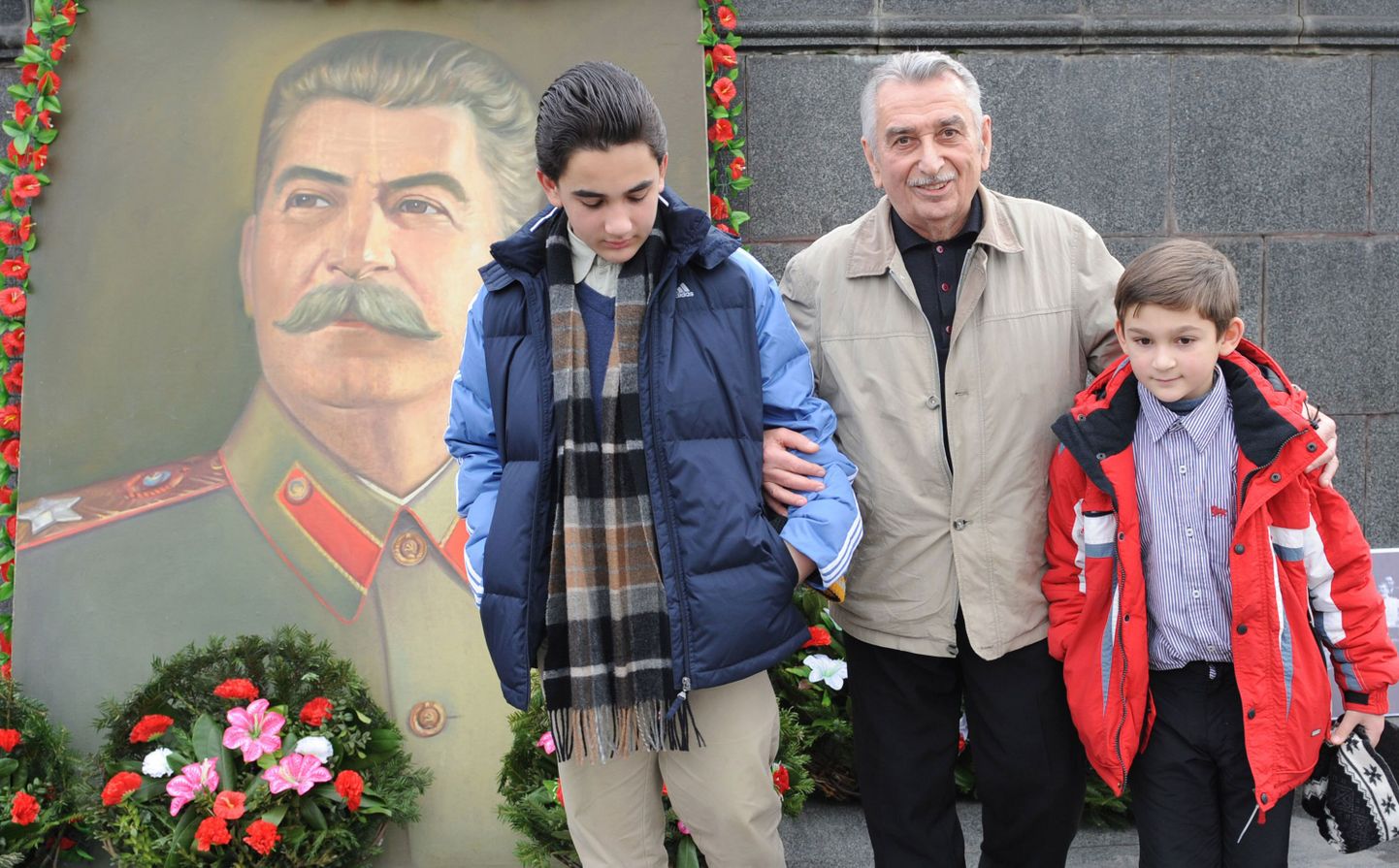 Евгений Джугашвили на фоне портрета Сталина.