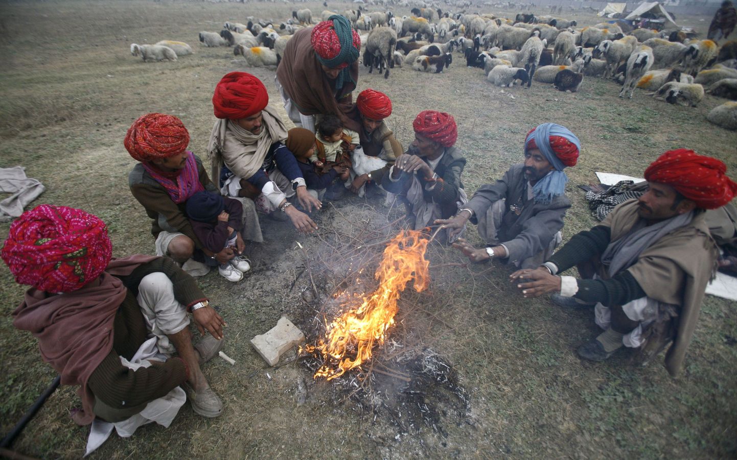 Indias Uttar Pradeshi osariigis elavad nomaadid soojendavad lõkke ääres käsi.