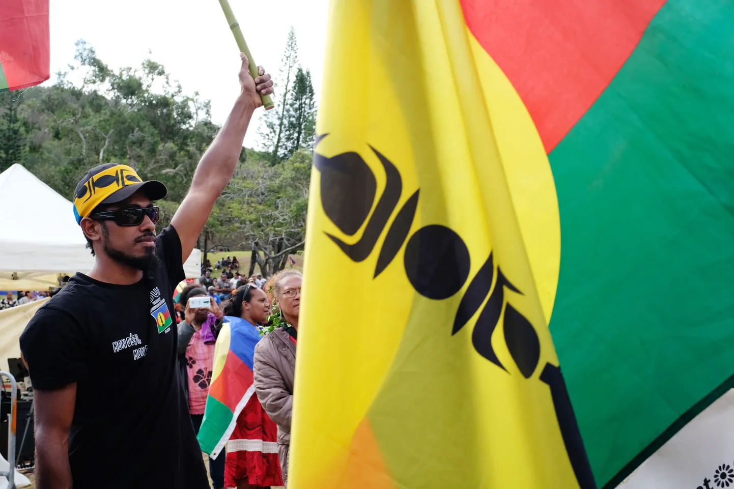 An Independence supporter stands past a flag of the Socialist Kanak National Liberation Front (FLNKS) during the last meeting of the FLNKS campaign for the "YES" to the self-determination referendum of New Caledonia, in Noumea on October 1, 2020. (Photo by Theo Rouby / AFP)