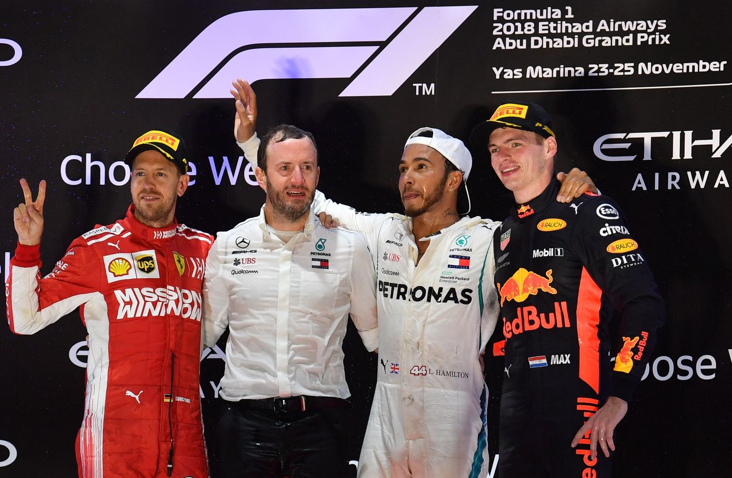 (From L) Ferrari's German driver Sebastian Vettel (2nd), head of Mercedes-Benz motorsport F1 communications Bradley Lord, Mercedes' British driver Lewis Hamilton (1st) and Red Bull's Dutch driver Max Verstappen (3rd) celebrate on the podium after the Abu Dhabi Formula One Grand Prix at the Yas Marina circuit on November 25, 2018, in Abu Dhabi. (Photo by Andrej ISAKOVIC / AFP)