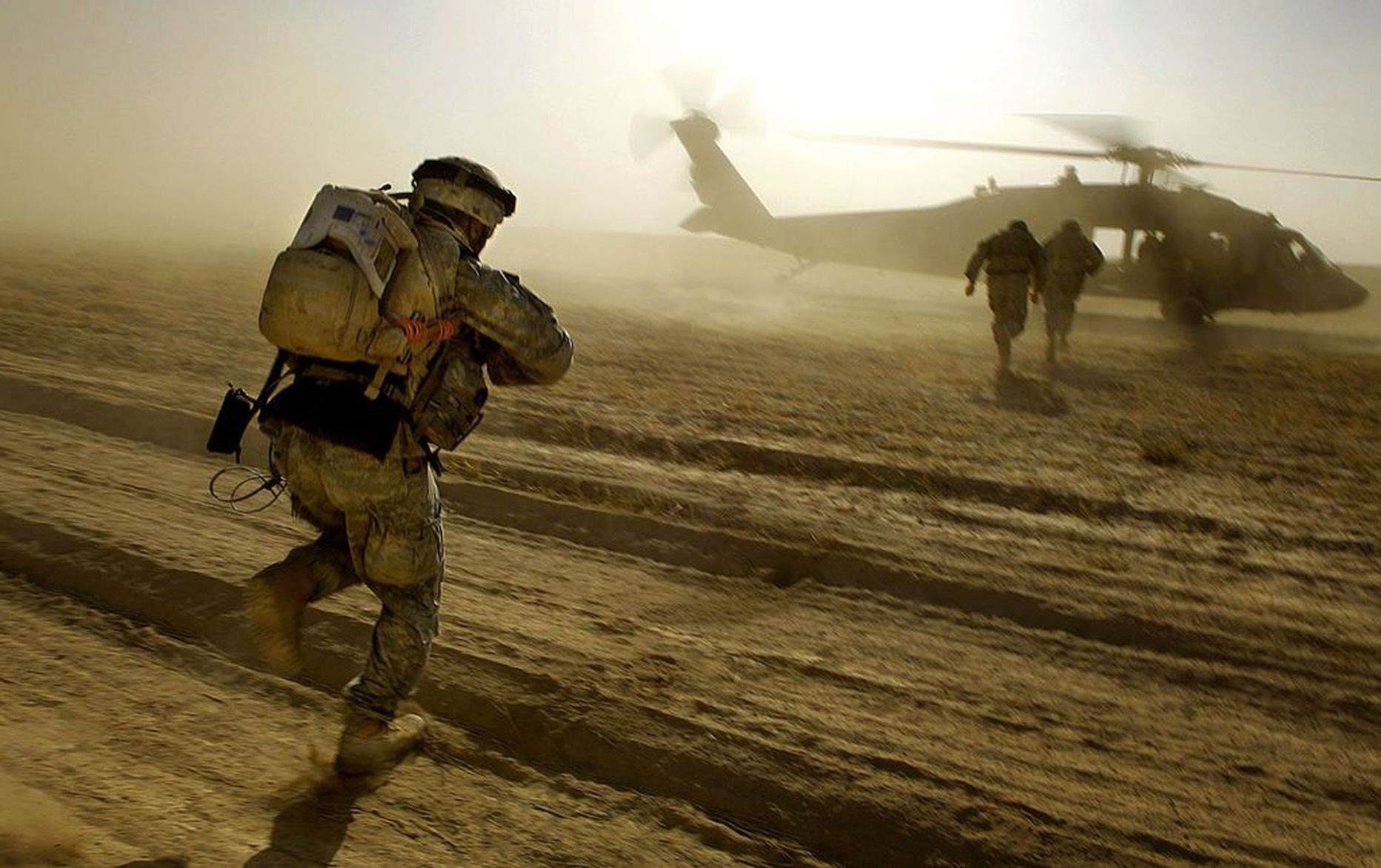 USA sõdurid jooksmas vaenlase tule eest Black Hawk helikopteri poole.